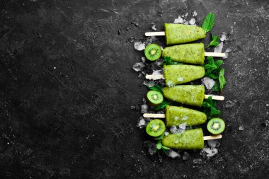 Buzlu ve kivili buzlu buzlu dondurma. Siyah taştan bir arka planda.