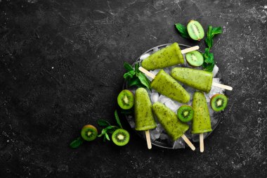 Bir tabak ev yapımı kivili dondurma. Siyah taştan bir arka planda.