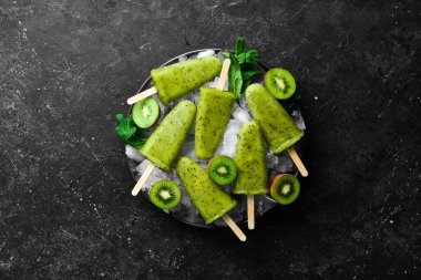 Bir tabak ev yapımı kivili dondurma. Siyah taştan bir arka planda.