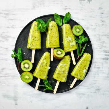 Bir tabak ev yapımı kivili dondurma. Siyah taştan bir arka planda.