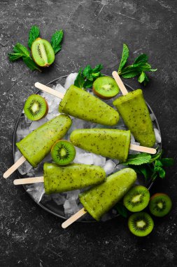 Bir tabak ev yapımı kivili dondurma. Siyah taştan bir arka planda.