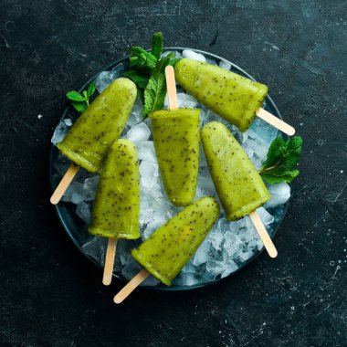 Bir tabak ev yapımı kivili dondurma. Siyah taştan bir arka planda.