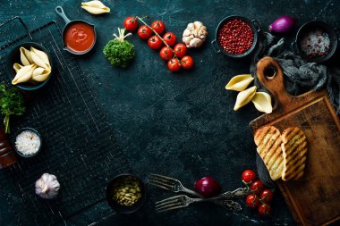 Yemek pişirmek. Sebzeler, baharatlar, şifalı otlar ve mutfak gereçleri. Taş zeminde. Üst görünüm.