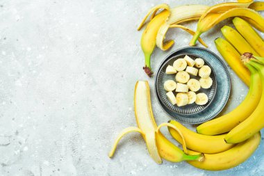 Bir kasede dilimlenmiş taze muzlar. Gri beton arka planda tropik muzlar. Üst görünüm.