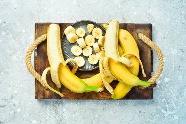 Bir kasede dilimlenmiş taze muzlar. Gri beton arka planda tropik muzlar. Üst görünüm.