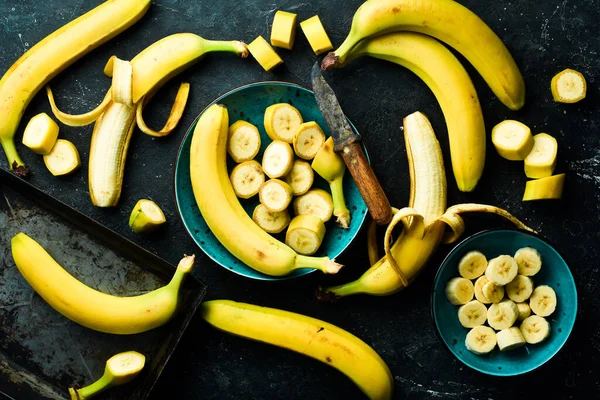 Manojos Plátanos Amarillos Rebanados Tazón Sobre Fondo Piedra Negra Vista —  Fotos de Stock