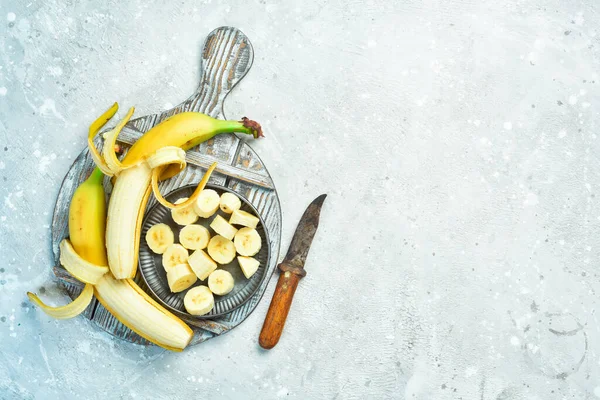 Fresh bananas sliced in a bowl. Tropical bananas on a gray concrete background. Top view.
