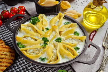 Et, krema sosu ve parmesanla doldurulmuş makarna. Kızartma tavasında. Geleneksel İtalyan yemeği. Taş zeminde. Tarif.