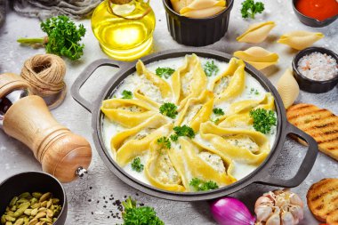 Et, krema sosu ve parmesanla doldurulmuş makarna. Kızartma tavasında. Geleneksel İtalyan yemeği. Taş zeminde. Tarif.
