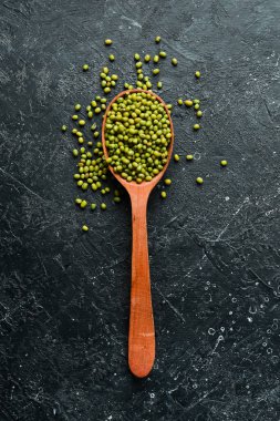 Mung fasulyesi, taştan bir arka planda tahta kaşıkta yeşil moong dalı. Üst görünüm.