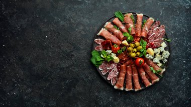 İtalyan jambonu, kurutulmuş domuz eti, parmesan peyniri, zeytin ve abur cubur. Üst Manzara. Gri taştan bir arka planda.