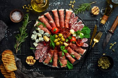 İtalyan jambonu, kurutulmuş domuz eti, parmesan peyniri, zeytin ve abur cubur. Üst Manzara. Gri taştan bir arka planda.