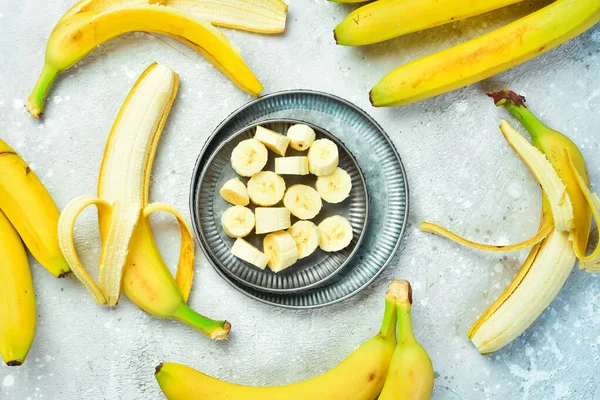 Fresh bananas sliced in a bowl. Tropical bananas on a gray concrete background. Top view.