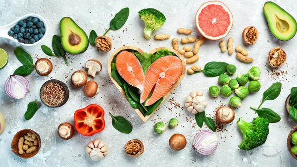 Foods good for the heart: nuts, salmon, avocados, spinach, mushrooms, berries. On a stone background. Top view.