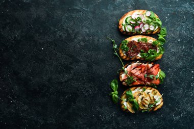 Siyah bir arka planda domatesli, jambonlu, sebzeli ve peynirli renkli sandviçler. Allah 'ım. Üst görünüm.