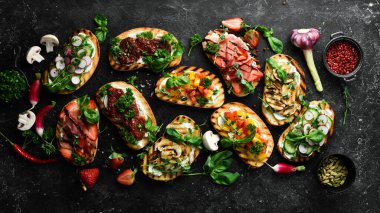 Siyah bir arka planda domatesli, jambonlu, sebzeli ve peynirli renkli sandviçler. Allah 'ım. Üst görünüm.