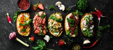 Siyah bir arka planda domatesli, jambonlu, sebzeli ve peynirli renkli sandviçler. Allah 'ım. Üst görünüm.