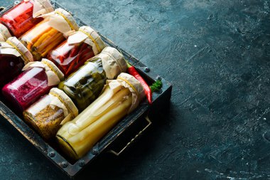 Kutuda lezzetli sebze turşusu kavanozları. Kriz durumunda yiyecek stokları. Taş zeminde. Üst görünüm.