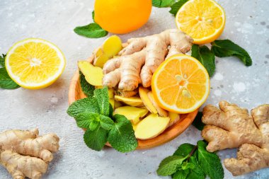 Tahta bir tabakta dilimlenmiş zencefil ve limon dilimleri. Yan görüş. Taş bir arka planda.