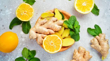 Tahta bir tabakta dilimlenmiş zencefil ve limon dilimleri. Yan görüş. Taş bir arka planda.