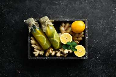 Limonlu, zencefilli ve nane yapraklı limonatalı düz kompozisyon. Vitamin Sağlıklı İçecek Konsepti. Siyah taştan bir arka planda.