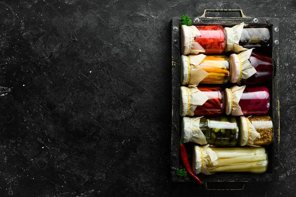 Kutuda lezzetli sebze turşusu kavanozları. Kriz durumunda yiyecek stokları. Taş zeminde. Üst görünüm.