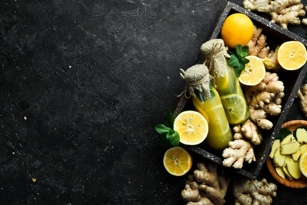Limonlu, zencefilli ve nane yapraklı limonatalı düz kompozisyon. Vitamin Sağlıklı İçecek Konsepti. Siyah taştan bir arka planda.