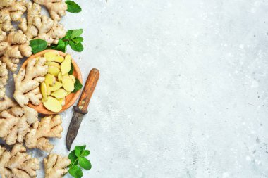 Tahta bir yüzeyde taze zencefil kökü dilimleri. Taş arkaplanda metin için boş alan.