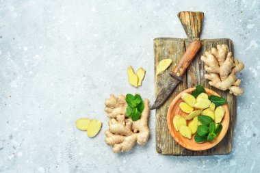 Tahta bir yüzeyde taze zencefil kökü dilimleri. Taş arkaplanda metin için boş alan.