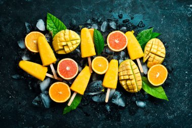 Buzlu tropik meyveli dondurma. Soğuk yaz meyveli tatlılar. Siyah taştan bir arka planda. Üst görünüm.