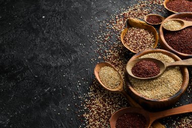 Ahşap mutfak masası manzaralı kinoa tohumları. Sağlıklı ve diyet süper gıda ürünü. Siyah taştan bir arka planda.