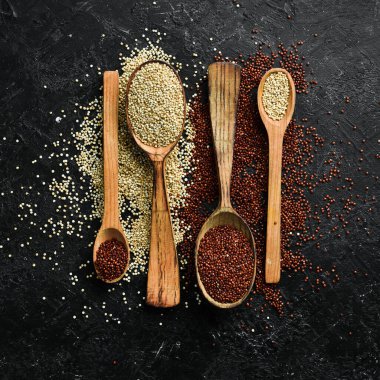 Ahşap mutfak masası manzaralı kinoa tohumları. Sağlıklı ve diyet süper gıda ürünü. Siyah taştan bir arka planda.