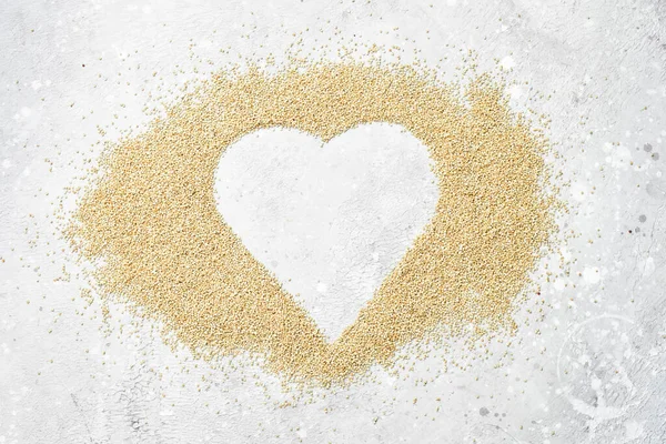 White quinoa. Set out in the form of a heart. On a gray stone background. Top view.