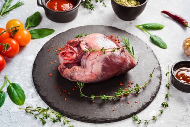 Baharat ve otlarla dolu siyah taş bir tabakta çiğ domuz kalbi. - Et. Taş bir arka planda.