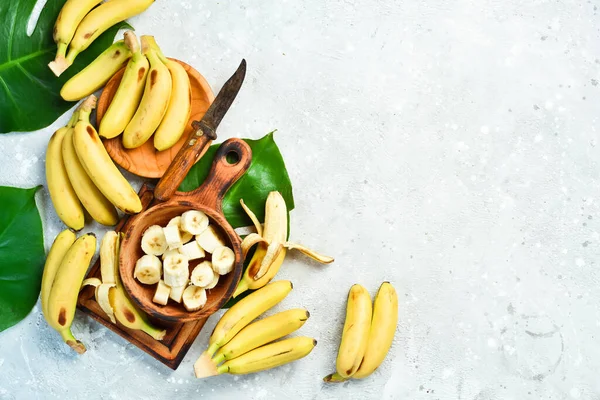 A bunch of bananas and a sliced banana baby on a table, delicious, natural. On a stone background. Free copy space. Top view.