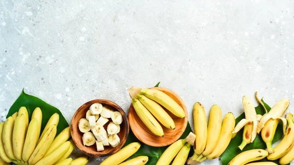 A bunch of bananas and a sliced banana baby on a table, delicious, natural. On a stone background. Free copy space. Top view.