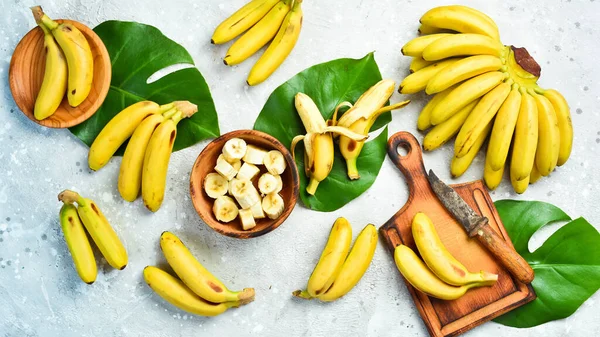 A bunch of bananas and a sliced banana baby on a table, delicious, natural. On a stone background. Free copy space. Top view.