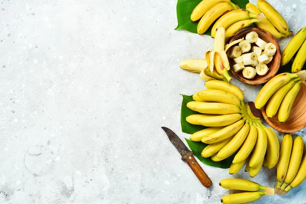 A bunch of bananas and a sliced banana baby on a table, delicious, natural. On a stone background. Free copy space. Top view.