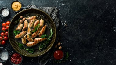 Biberiye ve baharatlı ızgara sosis. Barbekü. Siyah taştan bir arka planda.