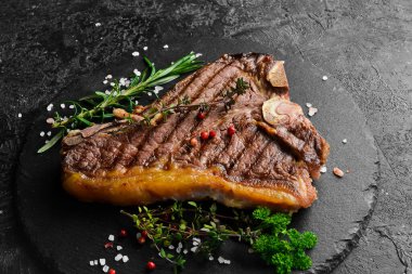 Izgara biftekli biftek. Siyah tabakta biftek. Üst Manzara. Siyah taştan bir arka planda.