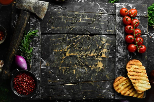 Stone black cooking background. Kitchen board with vegetables and spices. On a black stone background. Top view.