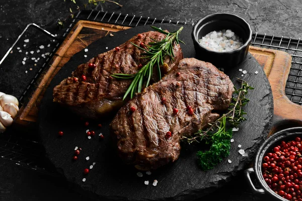 Dois Bifes Suculentos Ervas Especiarias Fundo Pedra Preta — Fotografia de Stock