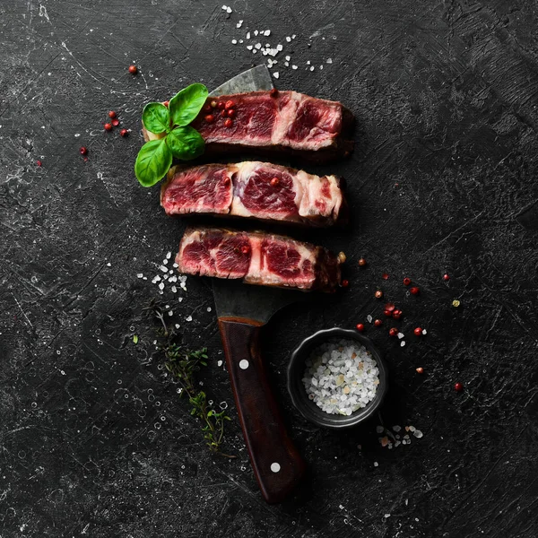 ナイフの上に肉ステーキ グリルステーキ テキストの空き容量 黒石の背景に — ストック写真