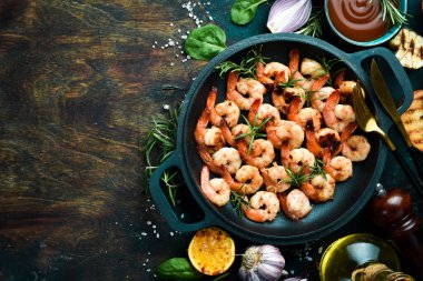 Tavada sarımsaklı ve limonlu kızarmış karides. Deniz ürünleri. Siyah taştan bir arka planda.