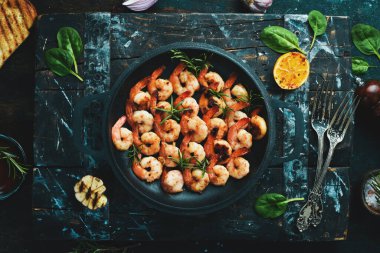 Tavada sarımsaklı ve limonlu kızarmış karides. Deniz ürünleri. Siyah taştan bir arka planda.