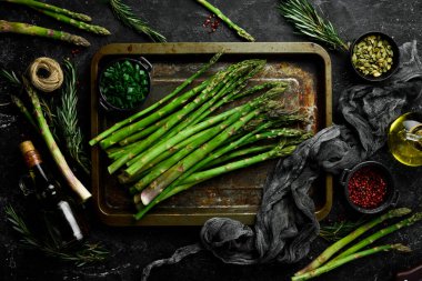 Kuşkonmaz pişiriyorum. Baharatlı yeşil kuşkonmaz. Sağlıklı yiyecekler. Taş zeminde. Üst görünüm.