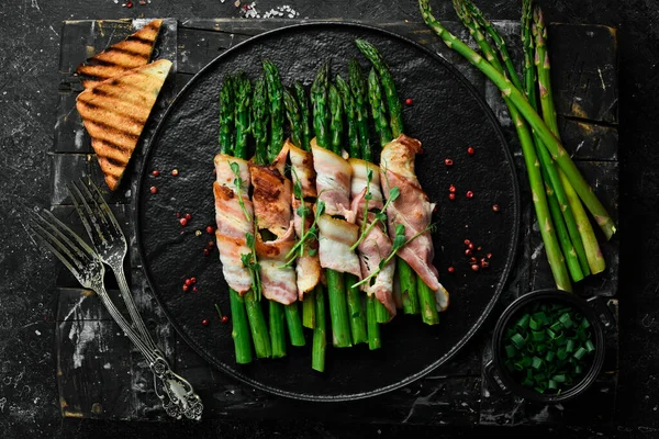 Pastırmayla sarılmış ızgara yeşil kuşkonmaz. Sağlıklı yiyecekler. Taş zeminde. Üst görünüm.