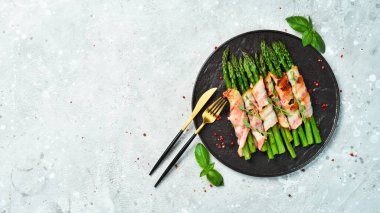 Pastırma ve fesleğenli ızgara kuşkonmaz. Taş zeminde. Üst görünüm.