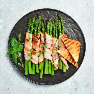 Pastırma ve fesleğenli ızgara kuşkonmaz. Taş zeminde. Üst görünüm.