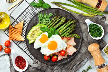 Kahvaltıda. Çırpılmış yumurta, kuşkonmaz, pastırma ve avokado. Siyah taştan bir tabakta.